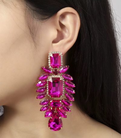 A woman wearing luxurious pink crystal dangle earrings with gold accents, adding a touch of glamour to her look.