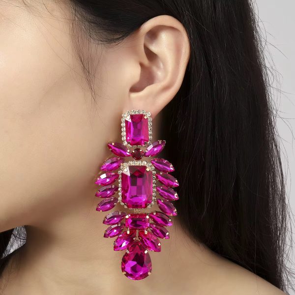 A woman wearing luxurious pink crystal dangle earrings with gold accents, adding a touch of glamour to her look.