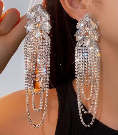 A close-up of a woman wearing luxurious crystal tassel earrings with marquise stones, adding a touch of glamour to her outfit.