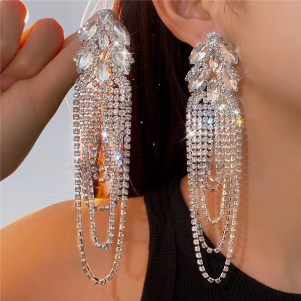 A close-up of a woman wearing luxurious crystal tassel earrings with marquise stones, adding a touch of glamour to her outfit.