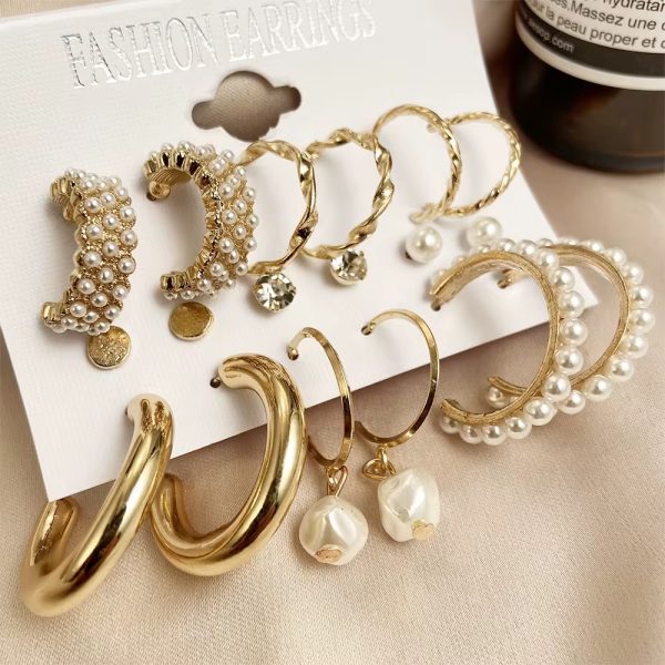 A set of 8 pairs of gold and pearl earrings on a white card, perfect for adding a touch of elegance to any outfit.