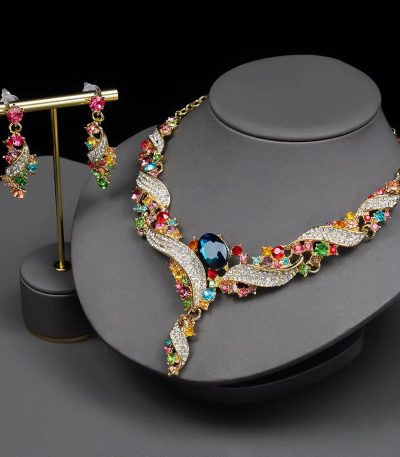 A luxurious multicolor gemstone necklace and earring set on a grey display, featuring gold-toned accents and sparkling crystals, perfect for adding a touch of elegance to any outfit.
