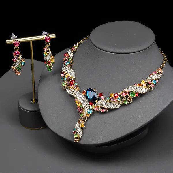 A luxurious multicolor gemstone necklace and earring set on a grey display, featuring gold-toned accents and sparkling crystals, perfect for adding a touch of elegance to any outfit.