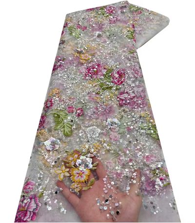 A hand holding a section of exquisite floral sequined tulle fabric, showcasing its intricate details and luxurious texture.
