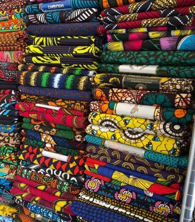 A colorful stack of African print fabrics with unique designs and patterns, perfect for fashion and textile enthusiasts.