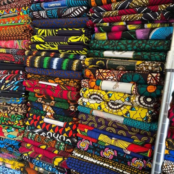 A colorful stack of African print fabrics with unique designs and patterns, perfect for fashion and textile enthusiasts.