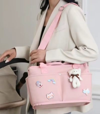 A woman in a white blazer holding a pink tote bag with bear embellishments and an adjustable strap, perfect for daily use.