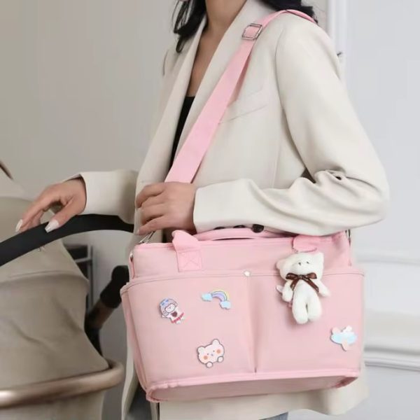 A woman in a white blazer holding a pink tote bag with bear embellishments and an adjustable strap, perfect for daily use.