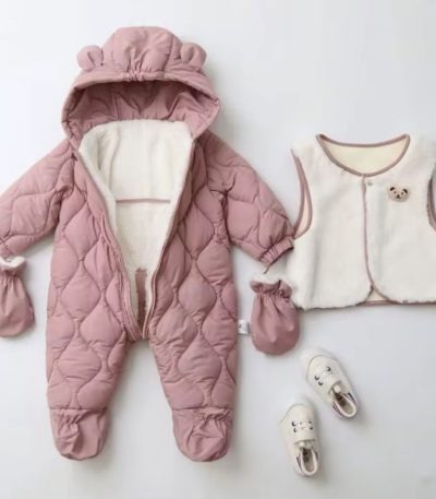 A beautifully arranged flat lay of a pink teddy bear baby snowsuit set, complete with mittens, a matching vest, and shoes on a white background.